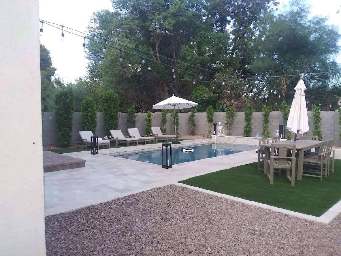 Finished backyard with a pool, pavers, and evening string lights